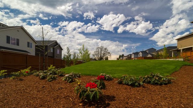 Time lapse of moving white clouds and blue sky over luxury homes and beautiful green lawn landscaping in Happy Valley Oregon one sunny spring day