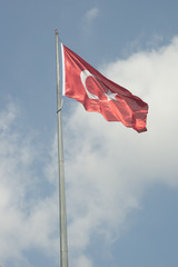 Turkish national flag waves in the breeze against the blue sky background