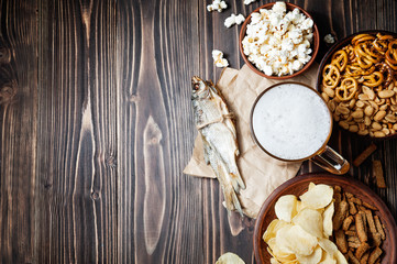 Lager beer glasses and snacks on wooden table. Nuts and dry fish. With copy space