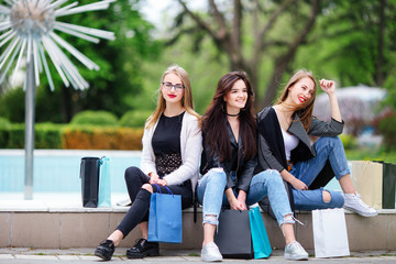 Three girls with shopping bags on park