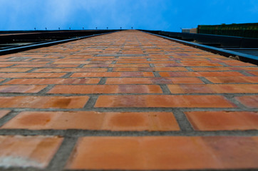 Orange brick wall of a skyscraper leaving in the blue sky. Height and infinity.