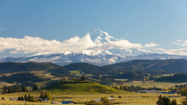 Time lapse movie of moving clouds and sky over snow covered Mt. Hood and rolling hills landscape pear orchards in Hood River Oregon spring season 4k uhd