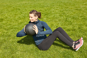 Fototapeta na wymiar Frau bei Fitnesstraining mit Gewichtsball im Garten