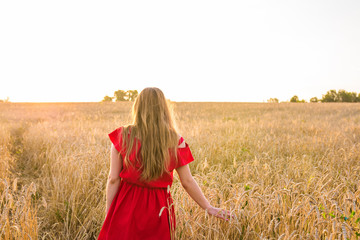 Obraz premium happiness, nature, summer, autumn, vacation and people concept - young woman in the field from back