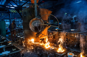 Foundry worker pouring hot metal into cast. Molten metal. Left over material from the steel manufacturing process is poured away on at a Steel Foundry