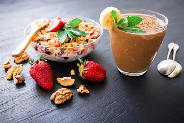 Diet breakfast. Oatmeal porridge with blueberries, strawberries and muesli on wooden background. Chocolate banana smoothie. Top view.