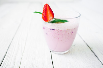 Blueberry smoothie with strawberry on wooden background. Fresh milkshake.