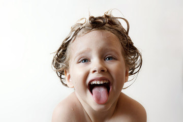 little girl with foam on the head laughs and shows tongue