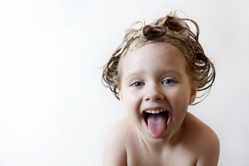 little girl with foam on the head laughs and shows tongue © olgamazina