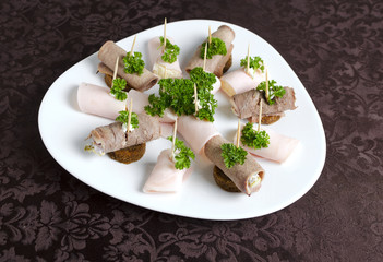 Rolls of ham and beef tongue on a white plate