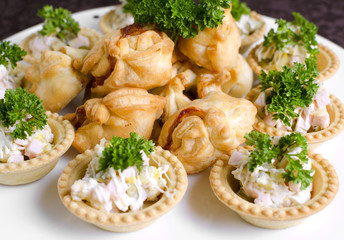 Tartlets with salad and snacks from puff pastry white plate