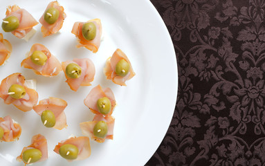 Meat canape with cheese on a white plate