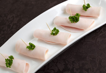 Rolls of ham on a white plate