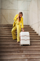 Young woman with suitcase rising up the stairs on railway station