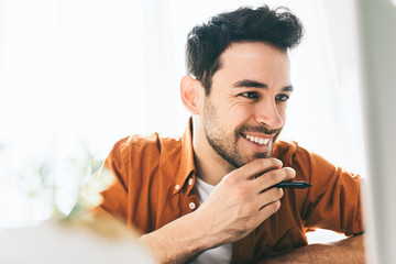 Close up shot of happy businessman with cheerful smile achieving life goals. Success and achievement concept. Happy Caucasian male student sitting next to computer, web conversation with friends.