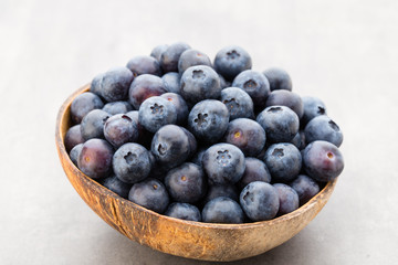 Fresh blueberries natural coconut in a bowl on a gray background.
