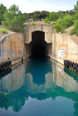 Concrete bunker shelter for submarines in adriatic sea. Beautifull clear blue water sea.