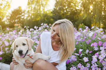 A blonde is playing with a Labrador puppy.