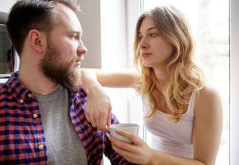 Young couple is drinking tea and coffee at home