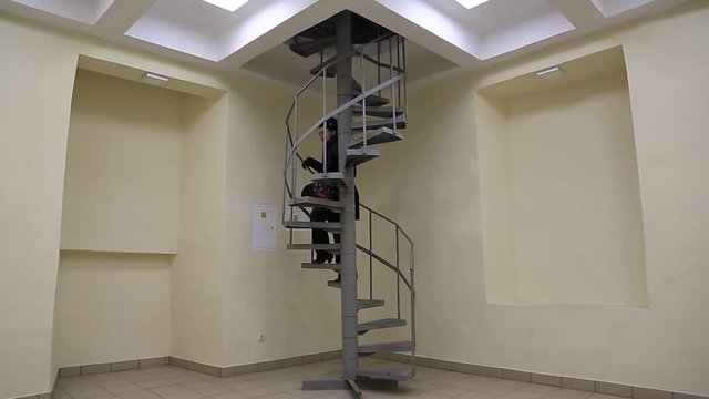 A woman rises up the spiral stairs