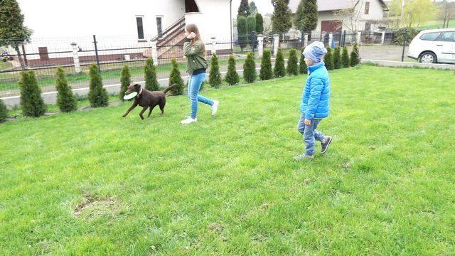 Children with dog playing frisbee in garden, super slow motion 240fps

