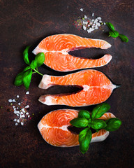 Raw fresh salmon fillet with aromatic herbs, spices, salt and lemon on wooden background. Healthy food concept, diet or cooking, protein product. Copyspace.