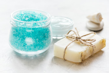 blue bath salt, body cream and shells for spa on white table background