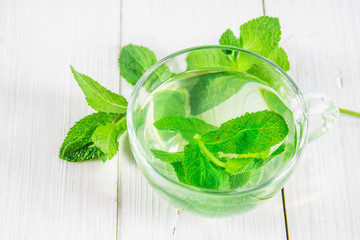 Mint tea in a cup on a white wooden table. Top view