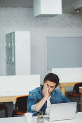 Serious young guy with beard working on laptop