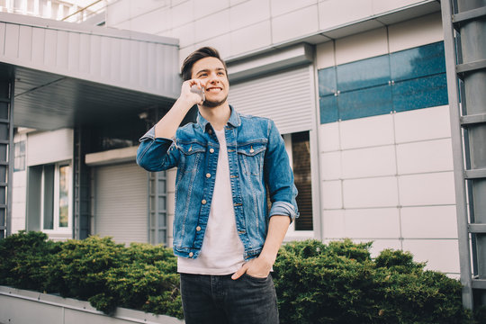 Young man standing outdoors, talking on the phone.