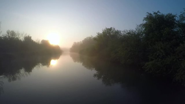 4K: Aerial Sun rising over misty river in marsh