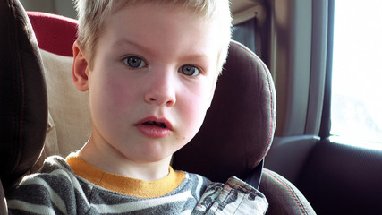 Little cute boy in a car seat. Pure emotions over child face.