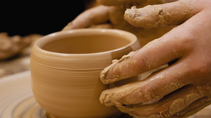 Potter is making clay pot bowl or vase ceramics porcelain on the potter's wheel. Creating pottery art and handicraft modelling creation.