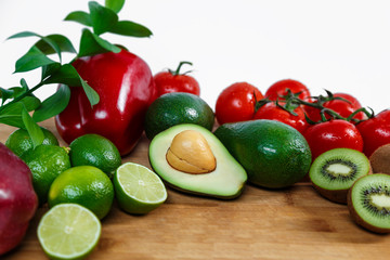 A selection of juicy fruits and vegetables on a wooden and white background.