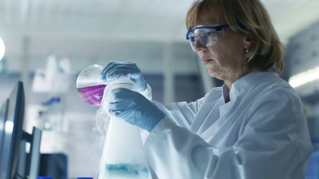 Senior Female Scientist Works with Samples in Isolation Glove Box. She's in a Modern Laboratory Equipped with State of the Art Technology. Shot on RED EPIC-W 8K Helium Cinema Camera.