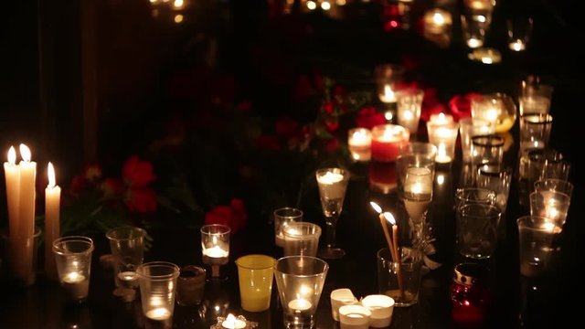 Close up of burning candles and flowers at the memorial in honor of terror victims