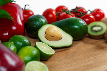 A selection of juicy fruits and vegetables on a wooden and white background.