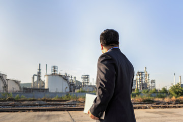 Businessman checking around oil refinery plant with clear sky