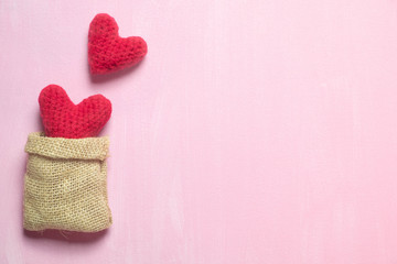 Fototapeta na wymiar Red crochet heart in sack bag on pink canvas background to represent the love