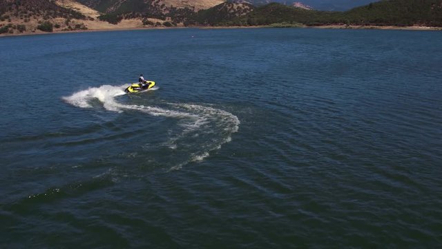 Aerial drone shot of man riding personal water craft on lake