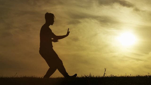 Lone male silhouette doing Tai Chi at sunset