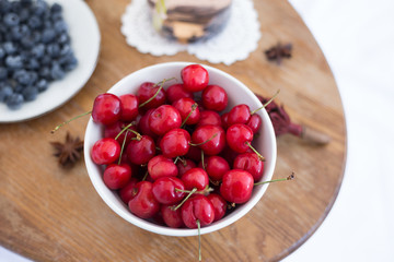 Cherry in the white bowl at the wood table. Fruit. Summer. Close up
