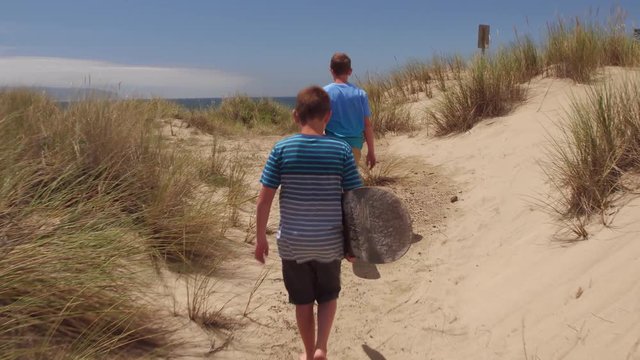 Boys walking with sandboards on dunes, Oregon