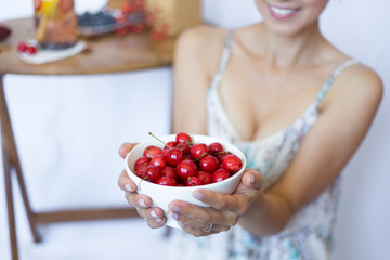 Female hands with Cherry in the white bowl. Fruit. Summer. Close up. Female holding bowl with cherry. Woman smile