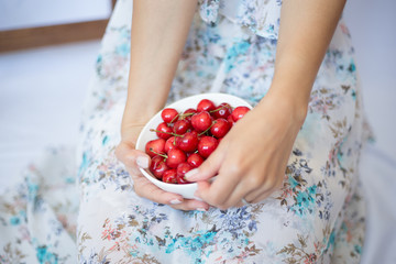 Female hands with Cherry in the white bowl. Fruit. Summer. Close up