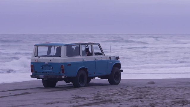 Group of friends driving suv at beach