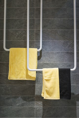 Yellow and black towel hang on the gray marble wall panel in modern bathroom.