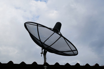 Silhouette of a satellite dish and the rain clouds on the sky