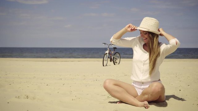 Young woman enjoying sunny summer day on sandy beach. Active girl with bicycle on seaside. Female tourist resting near to sea on fresh air 4K ProR es HQ codec