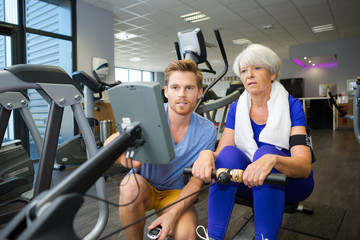 physiotherapist guiding senior woman on rowing machine
